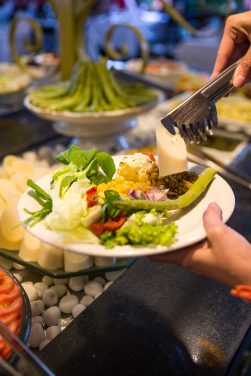 Prato sendo servido no buffet de saladas da Churrascaria Tertúlia contendo palmito, aspargos, entre outros.